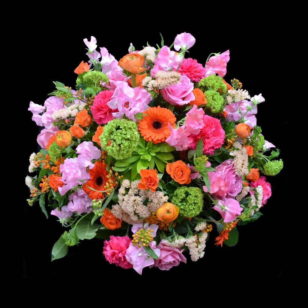 Rouwarrangement Dierbaar 50065 Rond arrangement met verschillende kleuren roze en oranje.