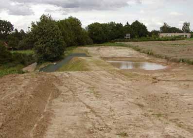 Langsheen de dam bevindt zich een met gras ingezaaide en bij voorkeur geprofileerde zone of grasgang waardoor het afstromende water en sediment worden geleid naar een lager gelegen