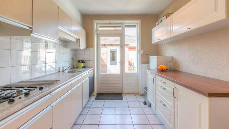 Keuken: De dichte keuken heeft een doorlopende tegelvloer en is uitgerust met een