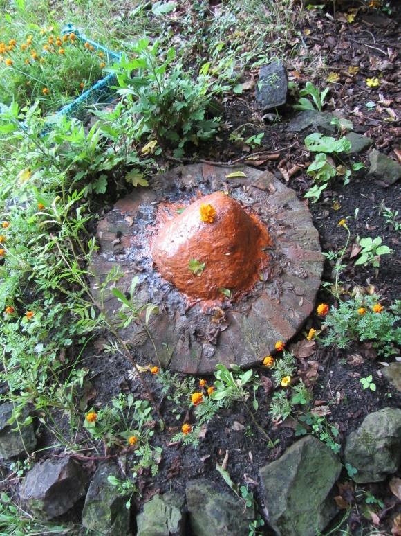 Stenen bij ingang dhuni De oranje steen vertegenwoordigt Hanuman, de zwarte steen staat voor Bhairava. Een keer per week legt iemand daar bloemetjes bij.