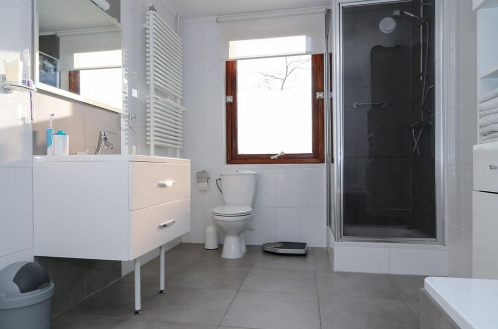 Ligging en indeling De badkamer is beschikt over een bad, een douche, toilet, wastafelmeubel en designradiator.