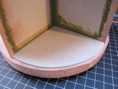 Leg om de ronding af te kunnen tekenen op twee delen van 10 x 10 cm eerst het chipboard in een vak van de carrousel. Schets een kwart cirkel/ronde lijn op je chipboard en knip of snij dit netjes af.