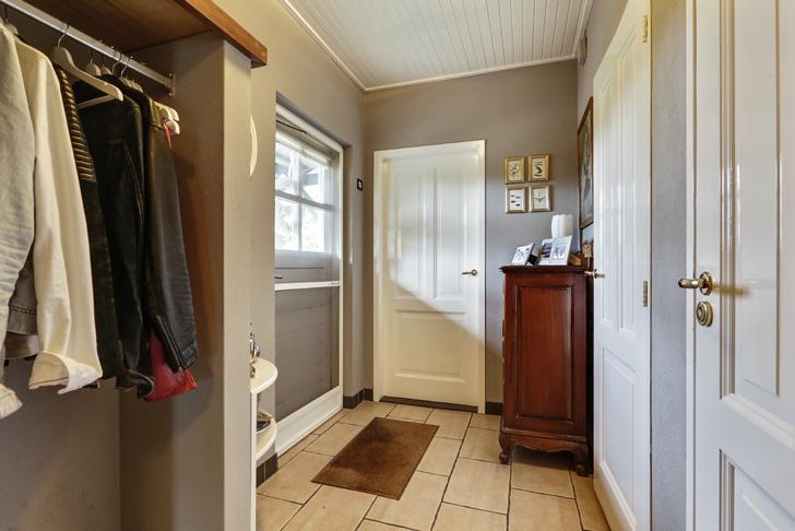 Aansluitend aan de keuken treft u een hal, die aan de achterzijde van de woning is gelegen. Voorzien van een provisiekast, een wit houten plafond en een tegelvloer.