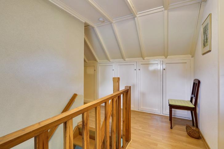 De slaapkamer aan de rechterzijde van de woning heeft een oppervlakte van ruim 20 m 2, is voorzien van een laminaatvloer en een wit houten plafond met inbouwspots.