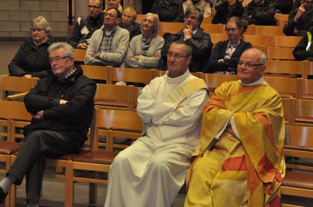 Van links naar rechts: Marcella, Luc, Dirk, Linda, Dirk, diaken Bart, Lut en pastoor Hugo luisteren naar het jaar overzicht van de parochie gebracht door Johan Van