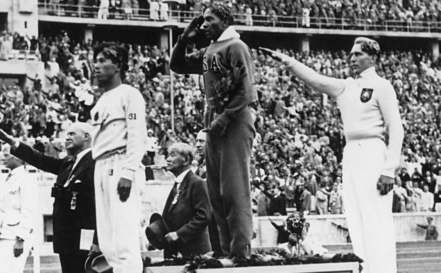 Vaardigheden bron 1 Een foto van de prijsuitreiking voor verspringen tijdens de Olympische Spelen in Berlijn, 1936: Toelichting: Links op het podium staat Naoto Tajima, Japan, bronzen medaille,