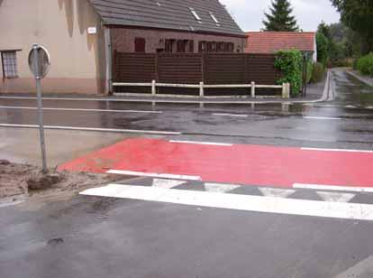 De rode coating en de wegmarkeringen vestigen de aandacht van de gemotoriseerde weggebruikers op de aanwezigheid van het dubbelrichtingsfietspad waarop fietsers voorrang hebben.