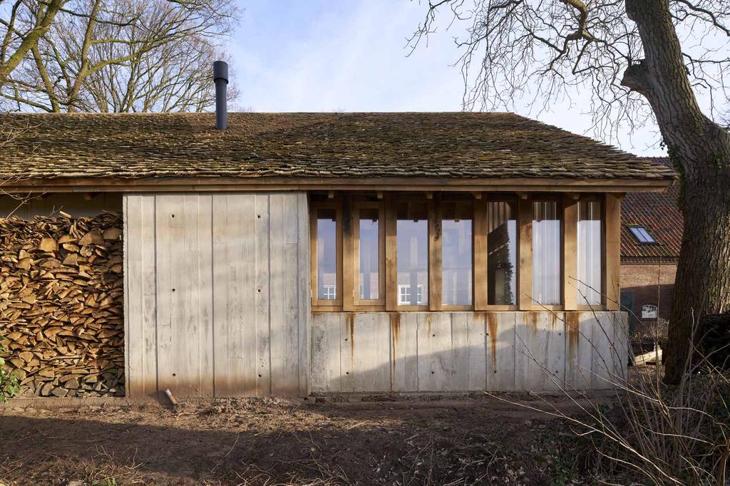 gevel aan de zijde van het weiland met rechts de werkplaats en links nissen voor