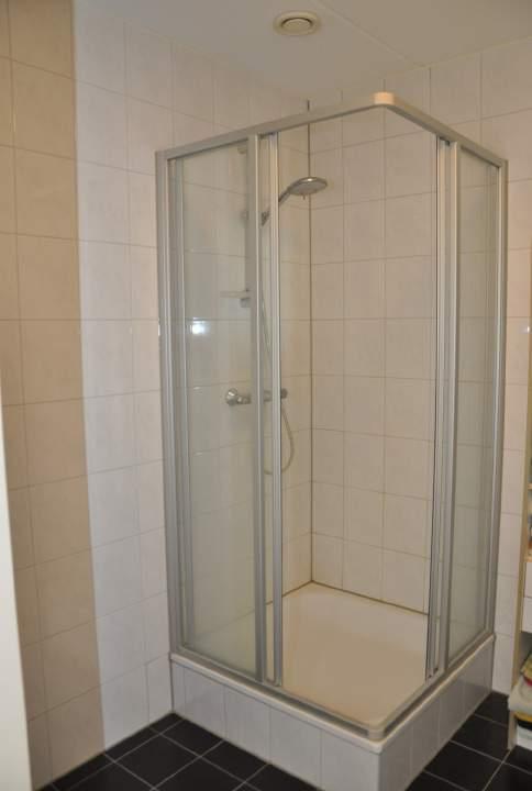 De geheel betegelde badkamer is voorzien van een douche met cabine en een vaste