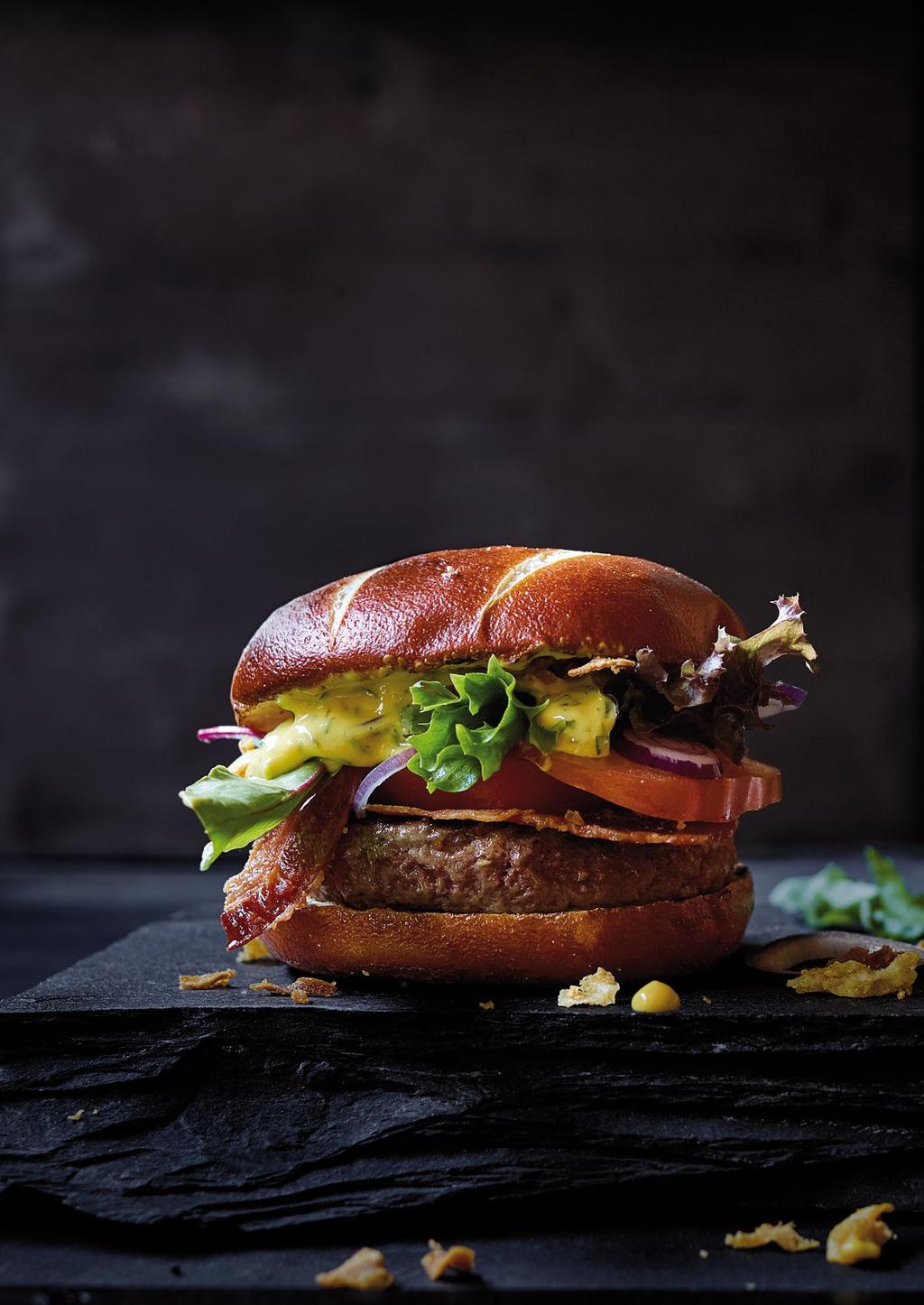 4 Bak de rundvleesburger in boter, ongeveer vijf minuten aan elke kant. 5 Snij de bagnat in twee. 6 Beleg de onderste helft met het rundvlees, de koolsla, de aardappelpartjes en de augurkjes.