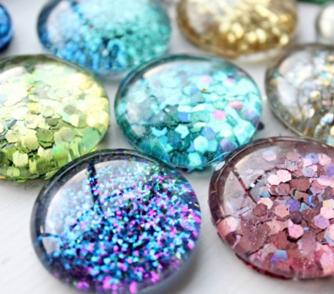 Glitterstenen verschillende kleuren glitters doorzichtige lijm verfkwastjes glasstene Optioneel: magneten. Zet bakjes klaar met daarin de glitters.