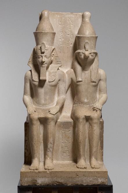 In dit dubbelbeeld zit rechts de god Horus. Zijn valkenkop vertelt ons dat hij een hemelse macht is. Naast hem zit de Egyptische farao Horemheb (1319-1305 v.