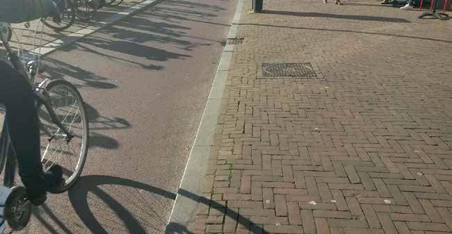 waar verkeer en verblijf in evenwicht zijn. De rijbaan is uitgevoerd in rood asfalt. Rijbaan en trottoir zijn van elkaar gescheiden door een smalle, lage natuurstenen stoeprand.