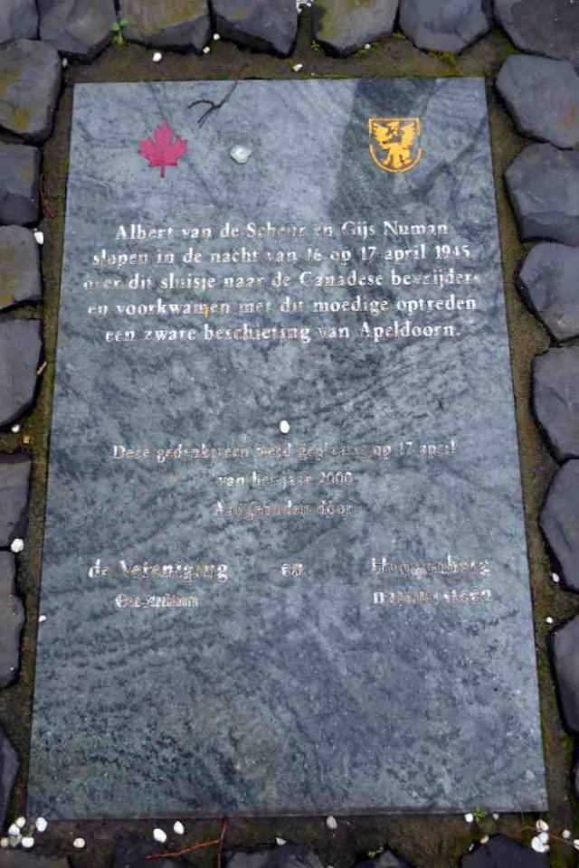 Op de steen staat de tekst: Albert van de Scheur en Gijs Numan slopen in de nacht van 16 op 17 april 1945 over dit sluisje naar de Canadese bevrijders en voorkwamen met dit moedige optreden een zware