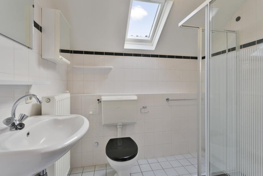 Badkamer De badkamer is tot plafondhoogte betegeld en voorzien van een toilet, een douche met douchescherm en een vaste wastafel met planchet en spiegel.