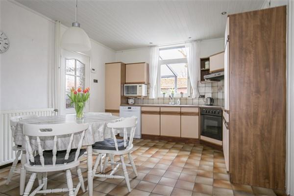De semi-open keuken is afgewerkt met een plavuizen vloer, deel schoonmetselwerk en deels grof schuurwerk wanden
