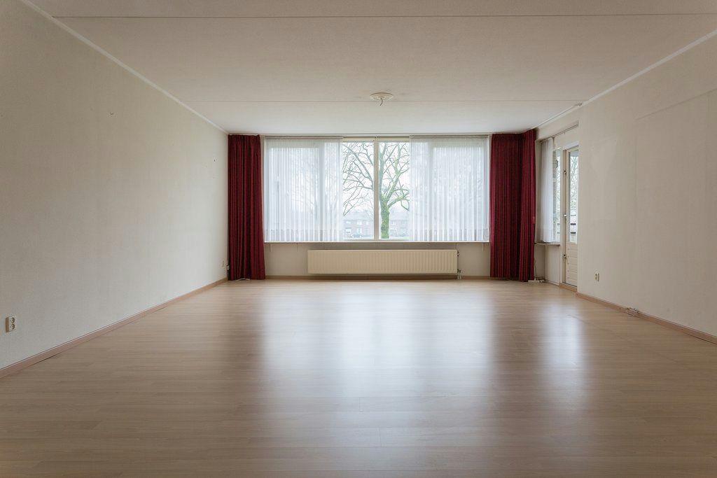 Woonkamer Royale woonkamer van ca. 43 m² (8.25 x 5.20 m) met stucwerk wanden, laminaatvloer en deur naar het balkon.