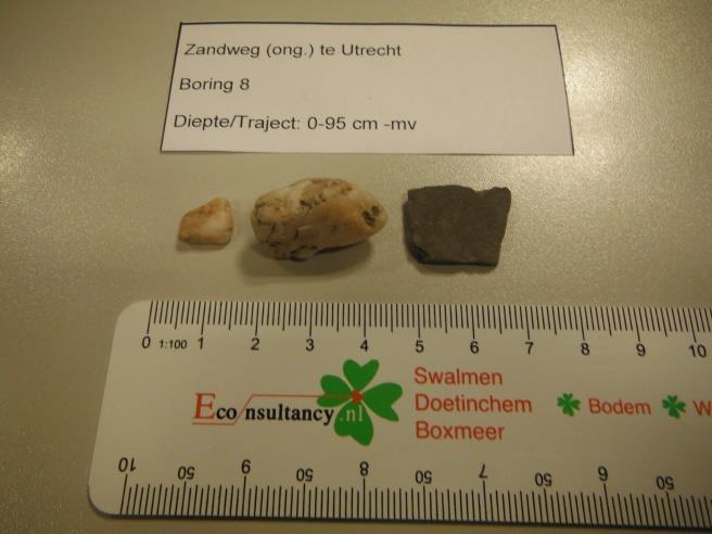 6 0-50 (bouwvoor/bovengrond) Enkele witte kiezels en een fragment Bataafs grijs aardewerk, bodemfragment van waarschijnlijk een pot, 1 e t/m 4 e eeuw na Chr. (Romeinse tijd).