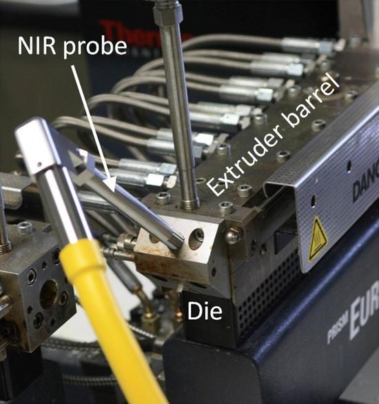 Figuur 1.2.: In-line implementatie van een NIR probe in de extruder. De Raman probe kan op dezelfde wijze in de matrijs bevestigd worden (Saerens et al., 2012).