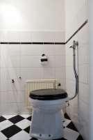 De toiletruimte is voorzien van een toiletpot en afgewerkt met tegels op de vloer en deels betegelde wanden. Boven de tegels zijn de wanden afgewerkt met glasvezelbehang.