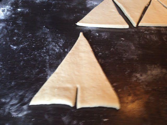 Maak een snee van 2 cm aan de korte kant van de driehoek en start hier met het vormen van de croissant.