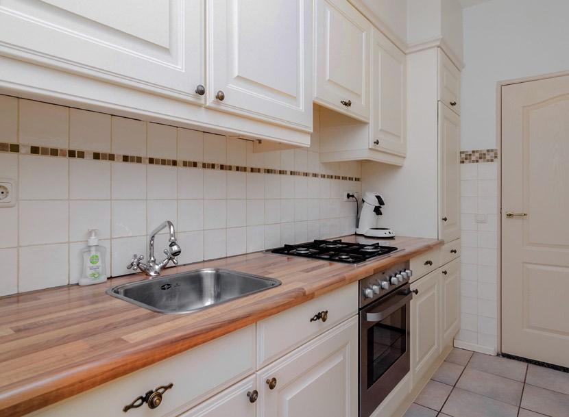 Semi-open keuken met een net keukenmeubel wandopstelling en toegang tot een praktische trapkast.