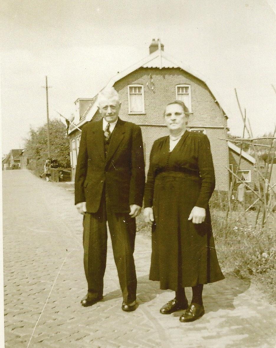 De vader en moeder van Oeds staan op de Rijksstraatweg met het gezicht naar hun woning op nr. 21.