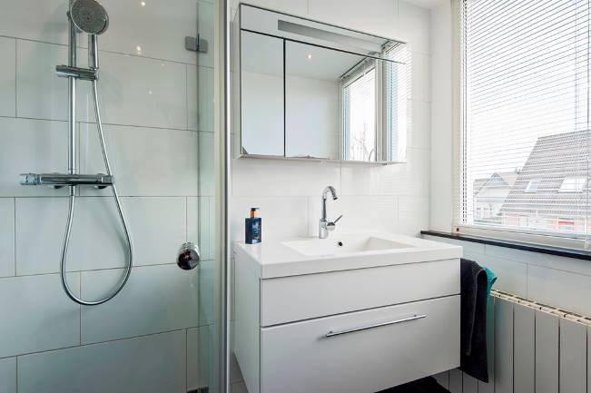 Door de toepassing van hardstenen elementen, ter plaatse van de vensterbank en het plateau boven het toilet en het bad heeft deze badkamer een luxe uitstraling gekregen.