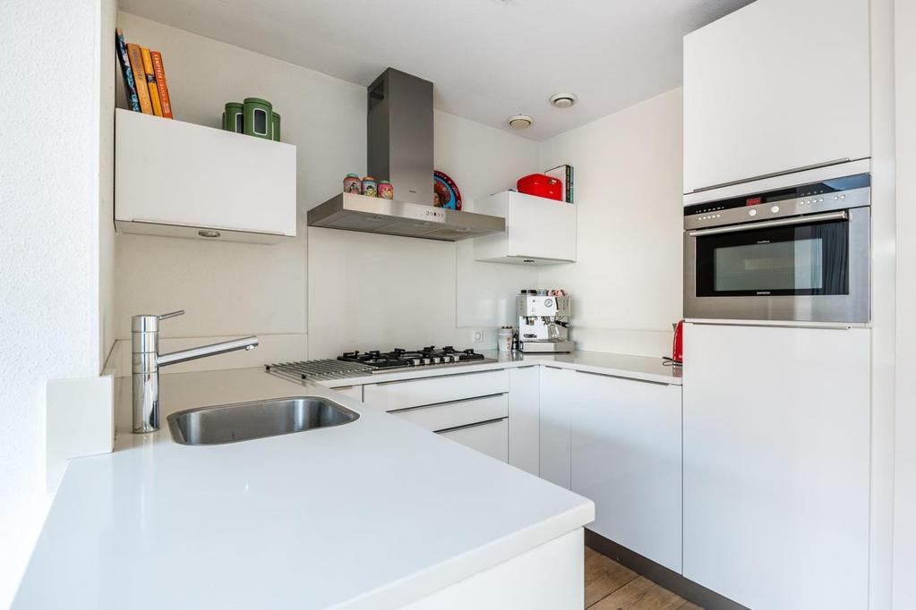 Keuken Een open keuken met een modern, U-vormig keukenmeubel welke is voorzien van een composiet