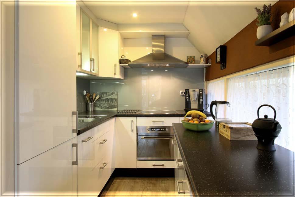 KEUKEN De hoogglans witte keuken is in 2012 geplaatst en uitgerust met een vierpits inductiefornuis met afzuigkap, een elektrische oven, vaatwasser, koelkast en een diepvries met drie lades.