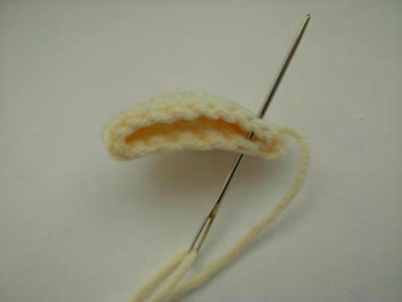 Naai de oren met een slingersteek in 9 steken dubbel. Splits de draad van de oren in tweeën en knip één draad af op 10 cm.