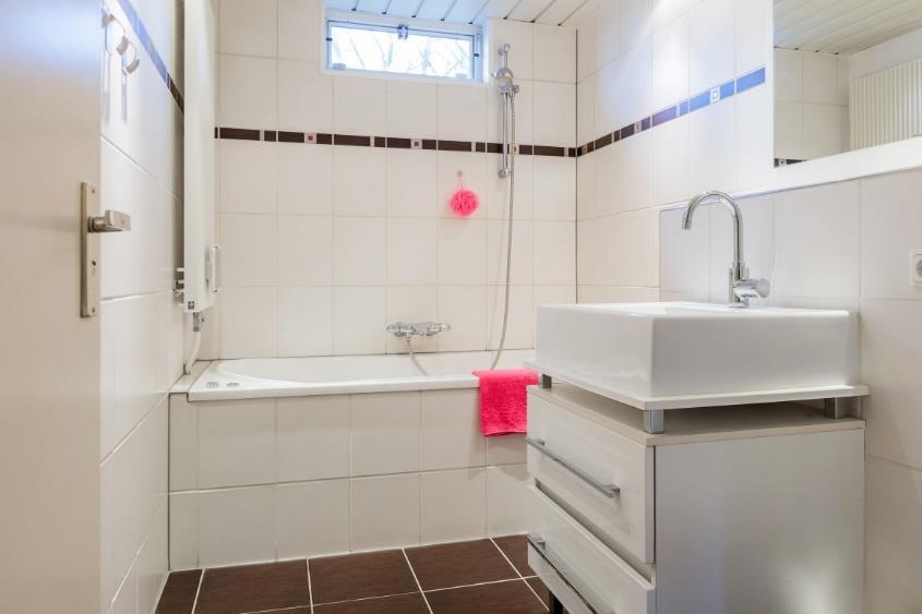 De badkamer: De moderne badkamer is fraai betegeld met een bruine vloertegel, een