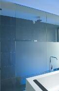 De douchewand en de wand tussen de badkamer en de aangrenzende dressing bestaan volledig uit glas, van plafond tot vloer, wat niet alleen de ruimtelijkheid van de badkamer
