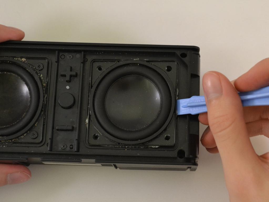 Stap 6 Met behulp van de opening gereedschap plastic, wrikken rond randen van de luidspreker aan lijm contact met de frontplaat los
