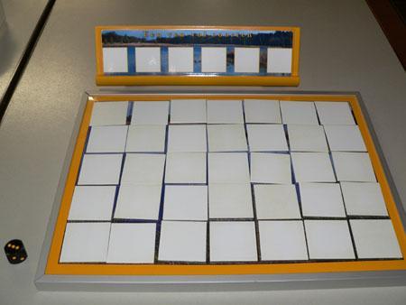 Begin Leg de speltegels met de witte kant naar boven op tafel, en meng ze. Leg de tegels daarna in een 7x5 raster op het spelbord.