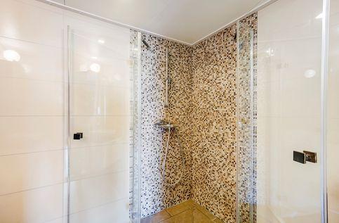De wanden achter de douchecabine zijn betegeld met mozaïek tegels wat voor een speelse en moderne uitstraling