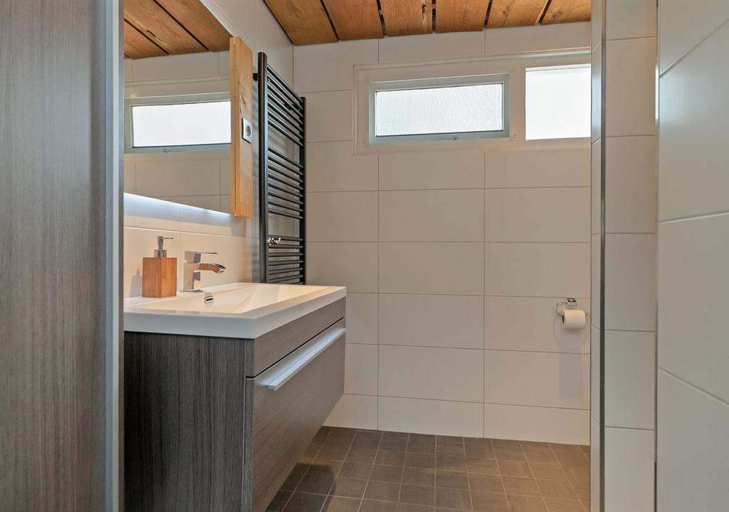 De badkamer is verder voorzien van een smaakvol afgewerkt plafond met eikenhout en inbouwspots.