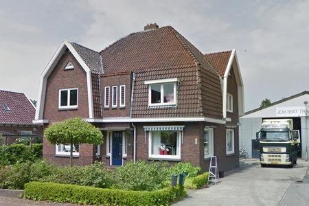 Uitgevoerd als dwarshuis met etalage aan rechter zijde van het voorhuis een aanbouw uit bouwtijd rechtsachter.