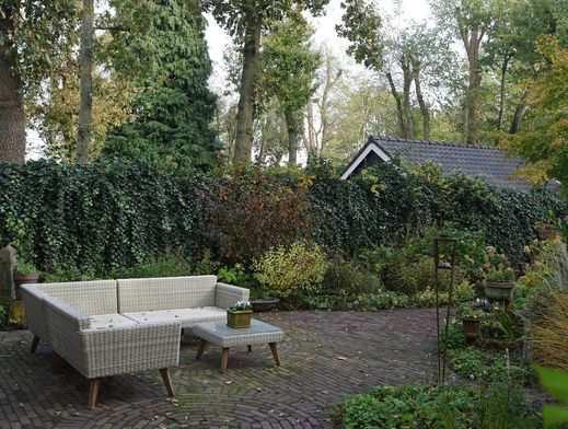 Tuin Via de hoge poort in de zijtuin en de openslaande deuren vanuit de zit-, werk- en