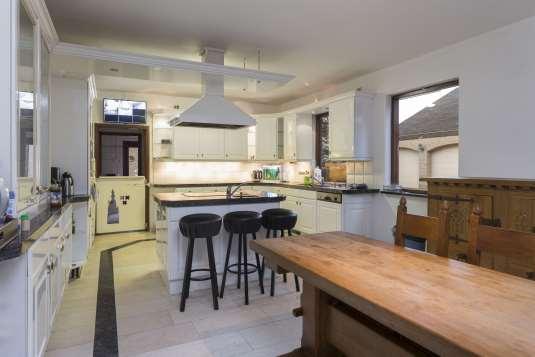 De keuken in hoekopstelling met kookeiland heeft een granieten aanrechtblad en diverse onder- en bovenkasten.