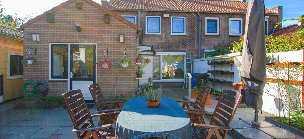 tuin Heerlijk, diepe zonnige achtertuin met terras en een grote verwarmde plantenkas met dubbel glas en automatische ontluchting.