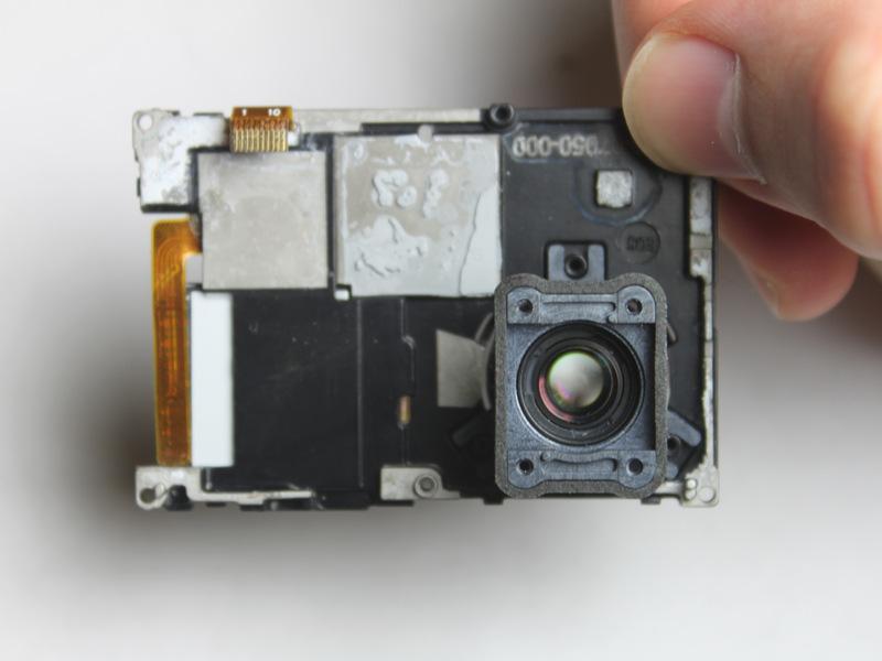 Zodra het lint kabel is aangesloten, kunt u de zwarte plastic beugel die de cameralens houdt verwijderen.
