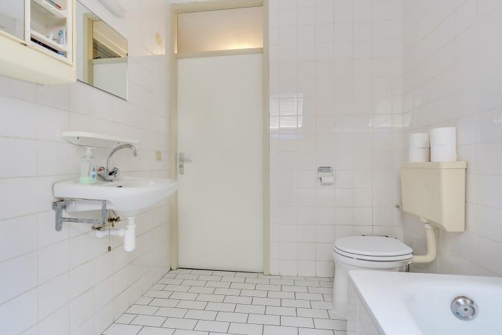 De geheel betegelde badkamer is voorzien van een bad, toilet en een wastafel.