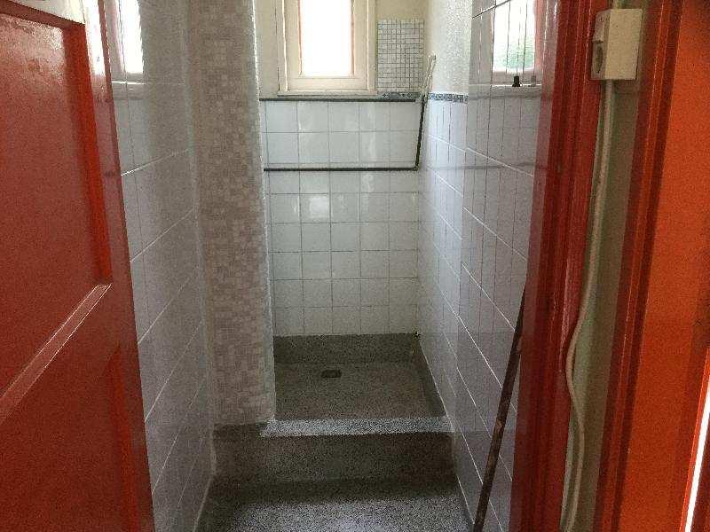 De badkamer is voorzien van tegelwerk en een granito vloer, achter