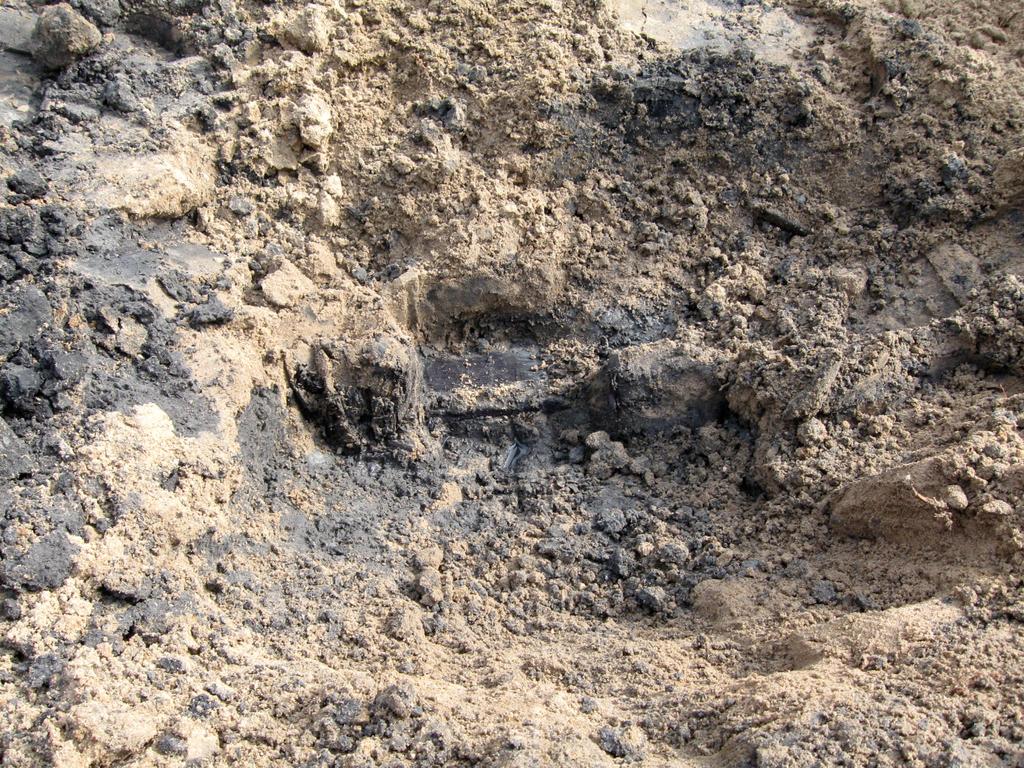 Circa 75 centimeter onder het maaiveld begint een donkergrijze zandlaag en zijn tevens enkele brokstukken puin waargenomen die vermoedelijk van