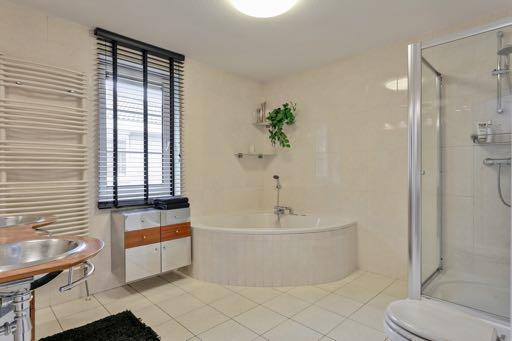 De luxe afgewerkte lichte badkamer is voorzien van een whirlpool bad met