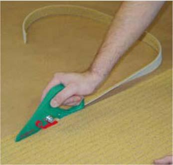 Installatie van getuft tapijt Pasmaken van één baan in een vertrek Snij het tapijt met een overmaat van ongeveer 5 cm, zowel in de lengte- als in de breedterichting.