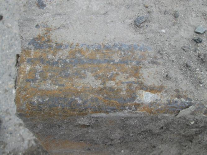 Foto van het oppervlak van de plank op 19,5 m mv voor het schoonmaken. De grondlaag was veelal gebarsten, waarschijnlijk door uitdroging, en kon gemakkelijk verwijderd worden.