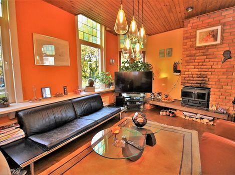 De gezellige woonkamer met kachel is voorzien van een massief eikenhouten vloer.
