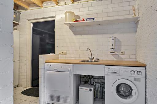 De bijkeuken heeft een tegelvloer en is voorzien van een wasmachine aansluiting, een aanrecht